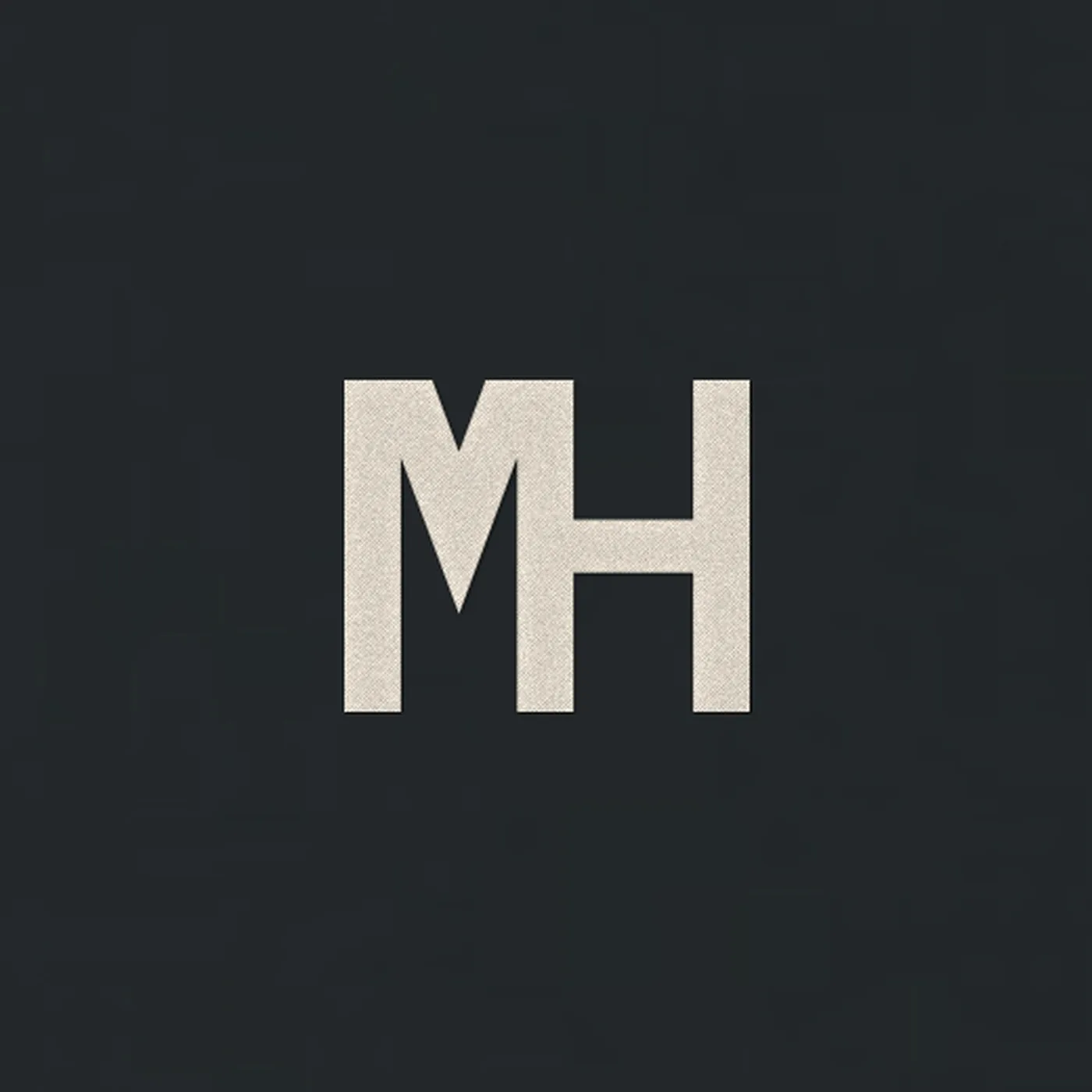 Close-up of the small cream MH monogram at the left chest embroidered on the MH Essential Hoodie