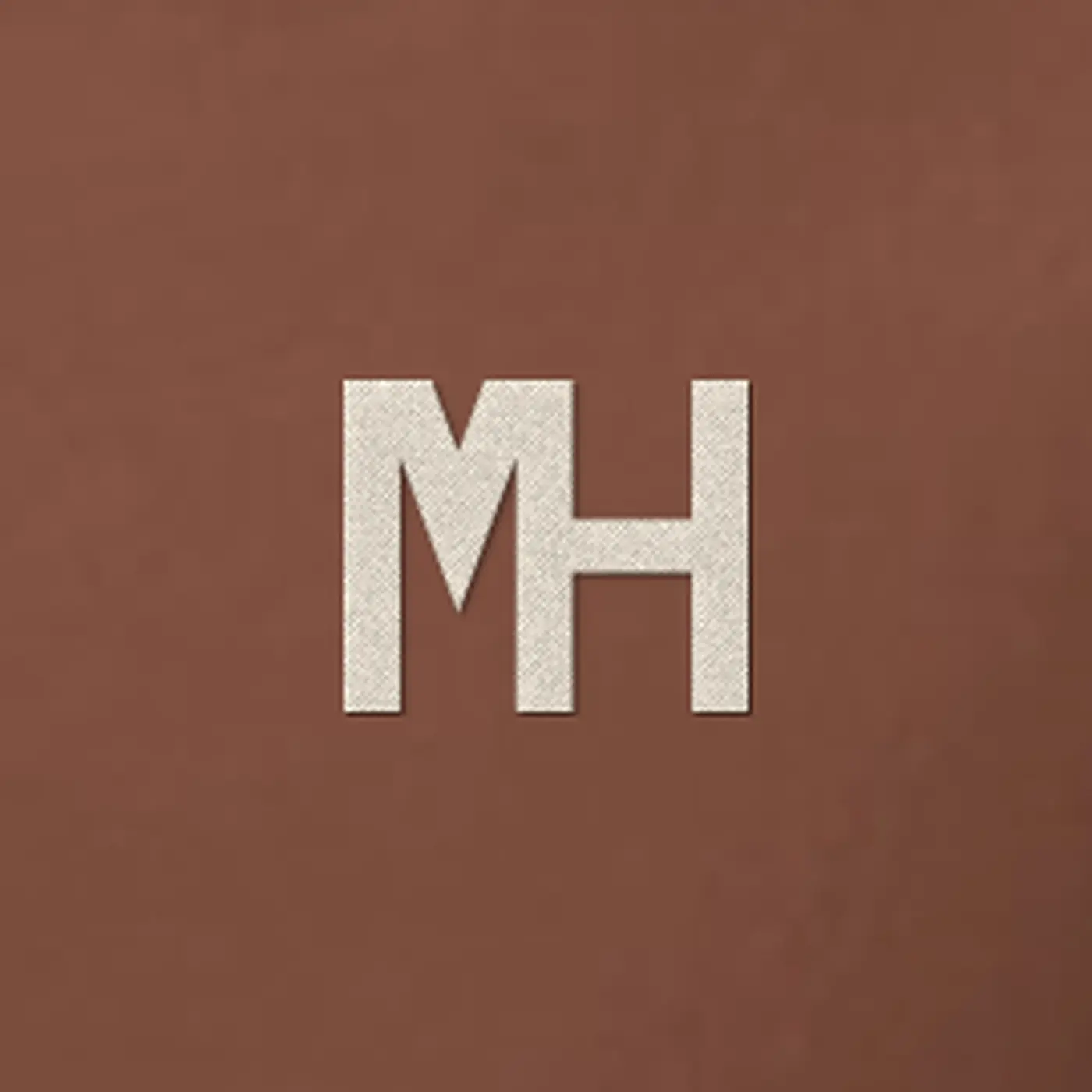 Close-up of a small cream MH monogram embroidered on the MH Relaxed Hoodie