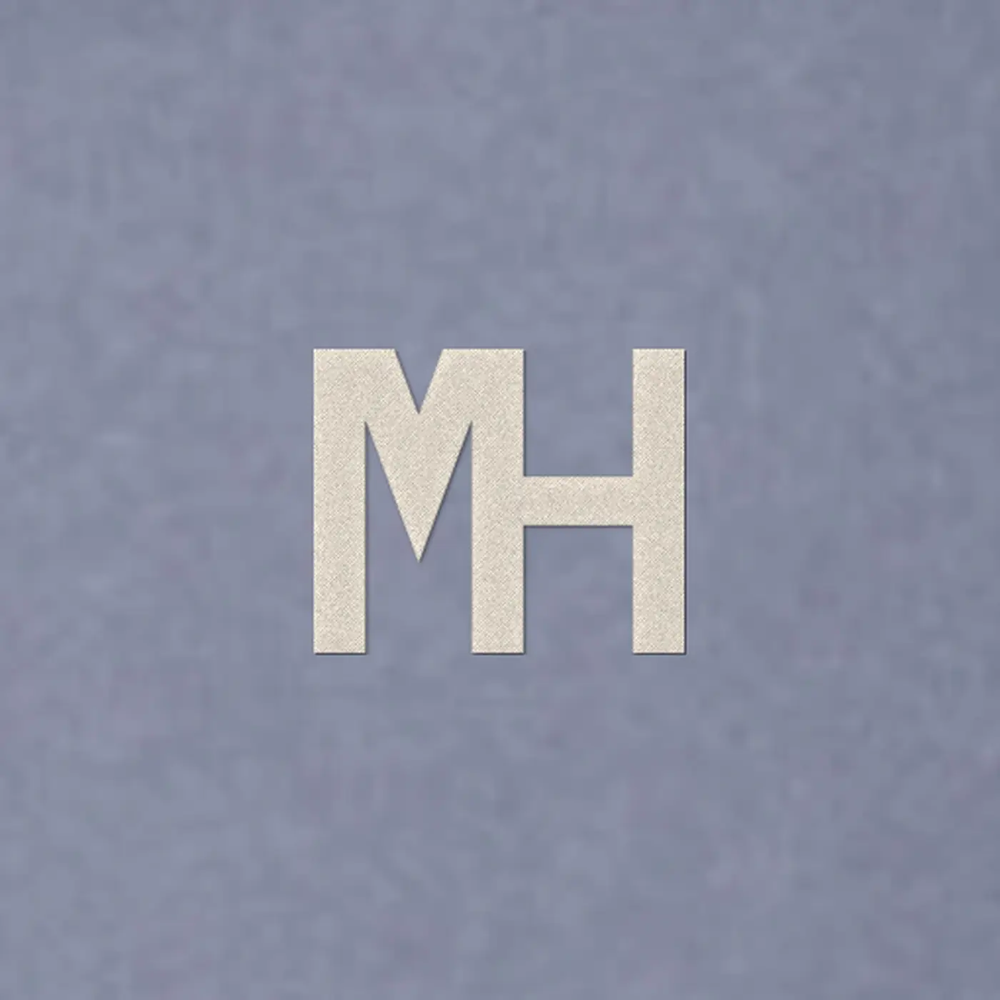 Close-up of a small cream MH monogram embroidered on the MH Washed Hoodie